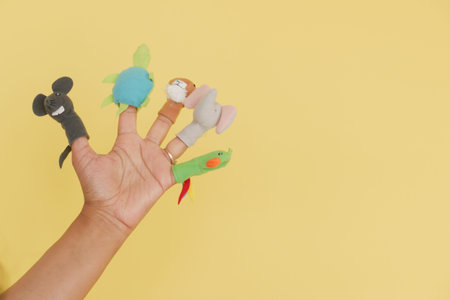 Children enjoying finger puppets on a bright yellow backgroundの写真素材