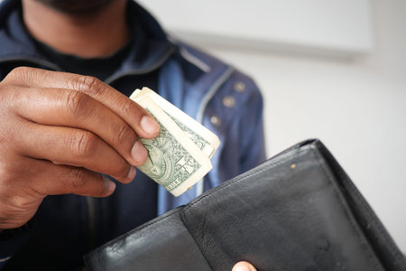 Holding cash while reaching into a wallet indoors at a store