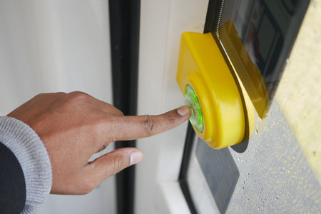 Individual activates a bright green bus stop button on a rainy day