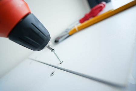 Screw being tightened with a drill in a workspace setting