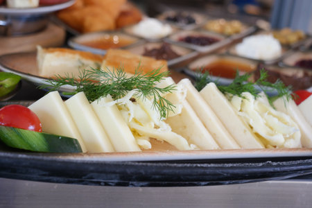 Delicious cheese platter with fresh vegetables and herbs on displayの写真素材