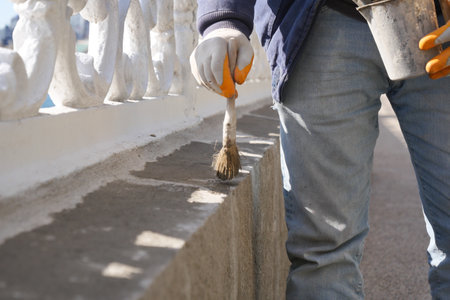 Worker painting a concrete wall with a brush during daylightの写真素材
