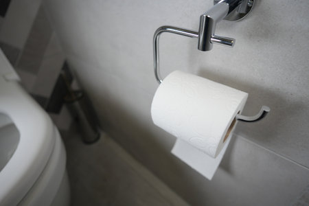 Clean bathroom with neatly hung toilet paper on wall holderの写真素材
