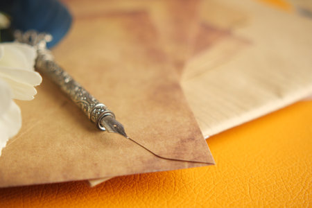 Old fountain pen resting on parchment paper with flower decorationの写真素材