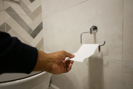 Hand pulling toilet paper roll in holderの写真素材