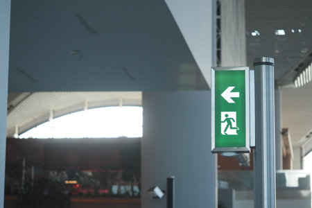 Emergency exit sign directing towards the left in a modern building