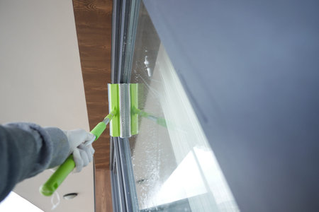 Rubber squeegee cleans a soaped window.