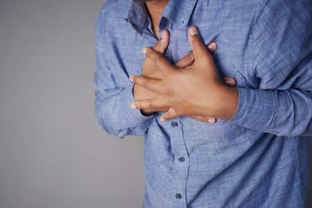 Man experiencing chest pain while wearing a blue shirt indoorsの写真素材