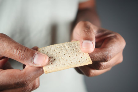 Person holding a textured cracker in a neutral background setting
