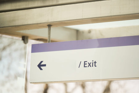 Sign pointing left toward exit in a public space