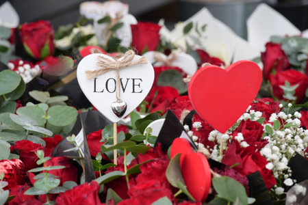Floral arrangement featuring red roses and heart decorations for loveの写真素材