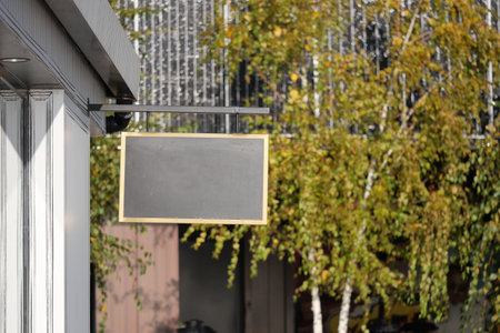 Blank sign hanging from a building in a sunny outdoor settingの写真素材