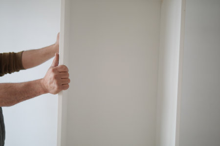 Moving a white shelf in an empty room during daylight hoursの写真素材