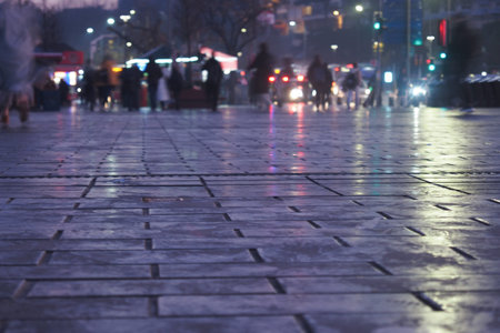Urban street at dusk with reflections from rain-soaked pavement