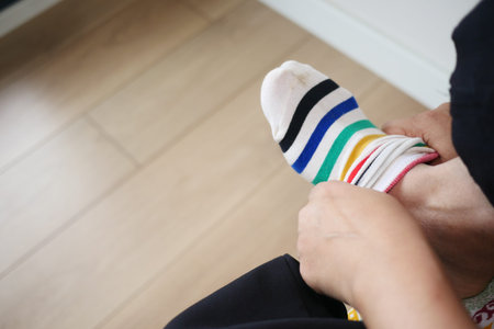 Putting on colorful striped socks in a bright room