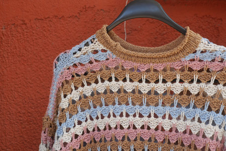 Handcrafted crochet sweater displayed against a rustic wall