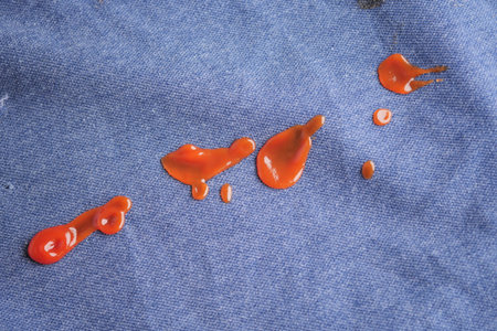 Red sauce splatters on blue fabric create vibrant contrast