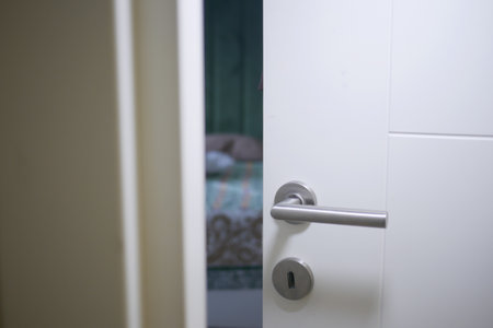 Door partially open revealing a softly lit bedroom interiorの写真素材