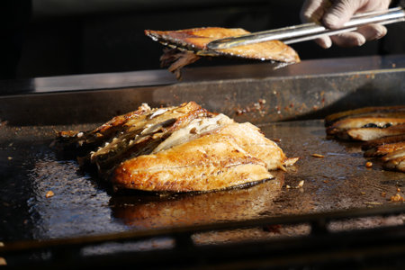 Grilling fresh fish at a local outdoor market during daylight hoursの写真素材