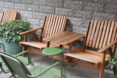Wooden chairs and small table arranged near a stone wallの写真素材