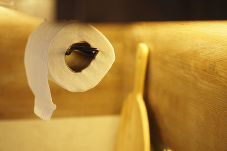 Paper towel roll hanging in a kitchen with wooden utensils nearbyの写真素材
