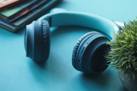 Headphones and plant on a teal surface with books in the background