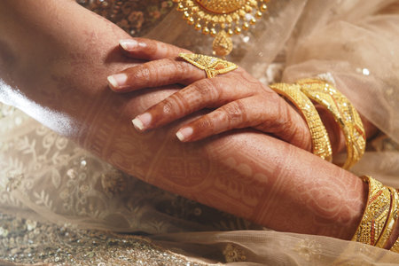 Elegantly adorned hands showcasing traditional gold jewelry and mehndi