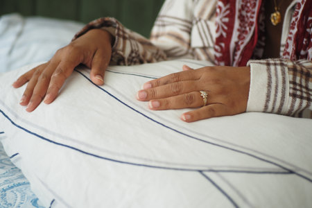 Hands resting on a soft pillow with a ring on displayの写真素材