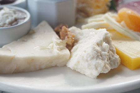 Variety of cheeses served on a platter with nuts and spreadsの写真素材