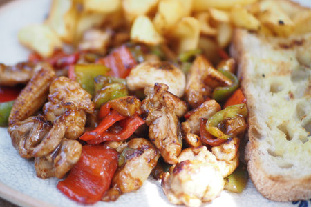 Savory chicken stir-fry with vegetables and toasted bread served hotの写真素材
