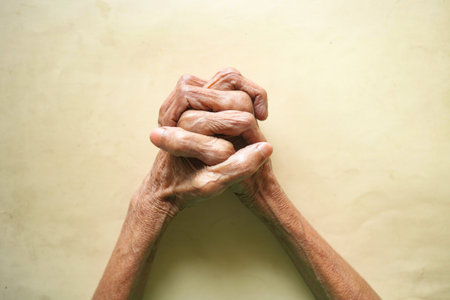 Elderly hands clasped together expressing hope and resilienceの写真素材