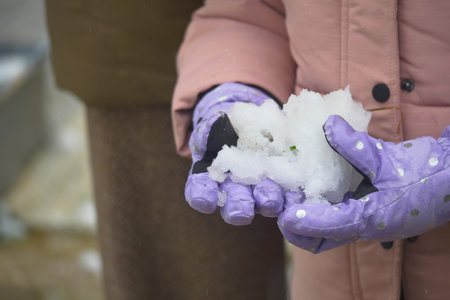 Child enjoying winter snow in a park during a snowy dayの写真素材