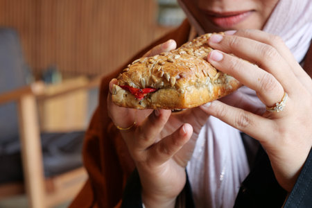 Woman enjoying a fresh sandwich in a cozy cafe settingの写真素材