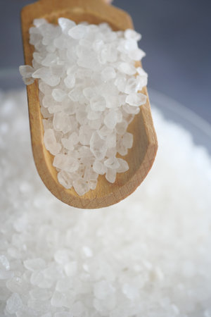 Natural sea salt being scooped with a wooden spoon from a bowl