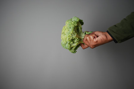 Broccoli held confidently against a gray backgroundの写真素材