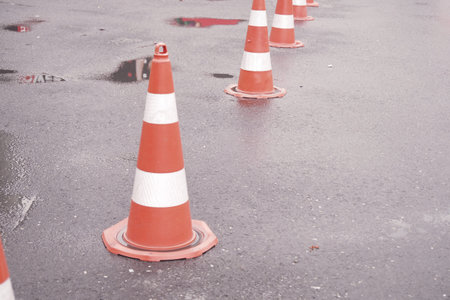 Traffic cones line a wet road after recent rainfall