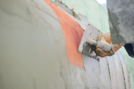 Worker applying plaster to a wall with a trowel at a construction site