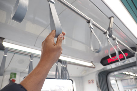 Commuter holds safety strap on urban transit train interior