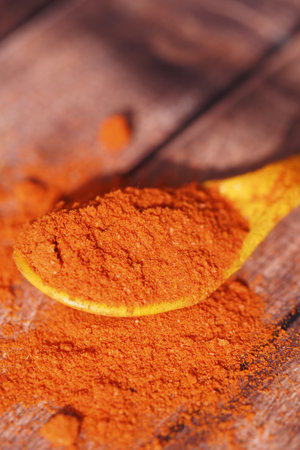 Red spice powder on wooden spoon ready for culinary useの写真素材