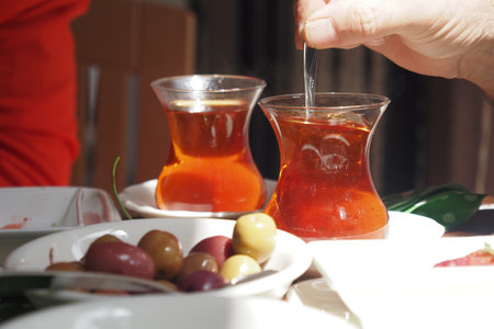 Enjoying turksih tea and olives at a cozy outdoor cafe during daytimeの写真素材
