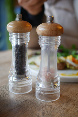 Salt and pepper shakers on a wooden table at a restaurant