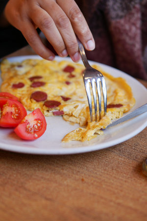 Enjoying a delicious homemade omelet with fresh tomatoes at breakfast