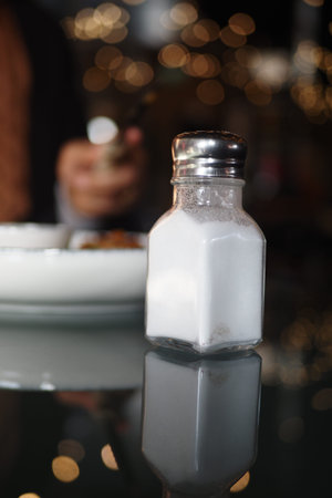 Sugar container on a reflective table in a cozy cafe settingの写真素材