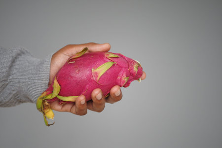 Holding a vibrant dragon fruit in hand for a close up viewの写真素材
