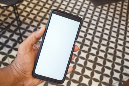 Smartphone held in hand on patterned floor in cozy indoor setting