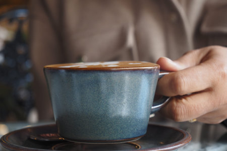 Enjoying a warm cup of coffee at a cozy cafe in the morningの写真素材