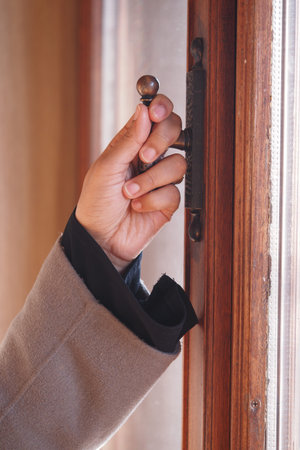 Hand grasping a vintage door handle in a cozy interior