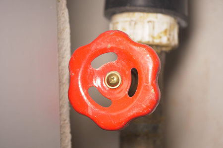 Bright red valve handle on a pipe ready to be turned for maintenance