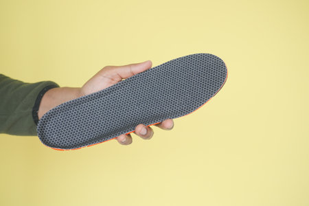 New shoe insole being held against a bright yellow backgroundの写真素材