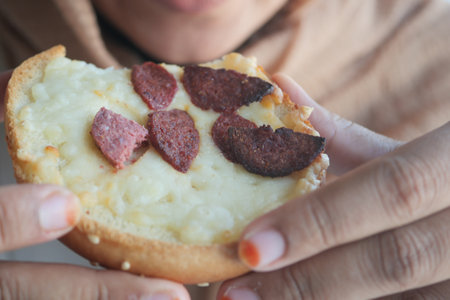 Delicious close-up of a savory bun topped with sausage slicesの写真素材